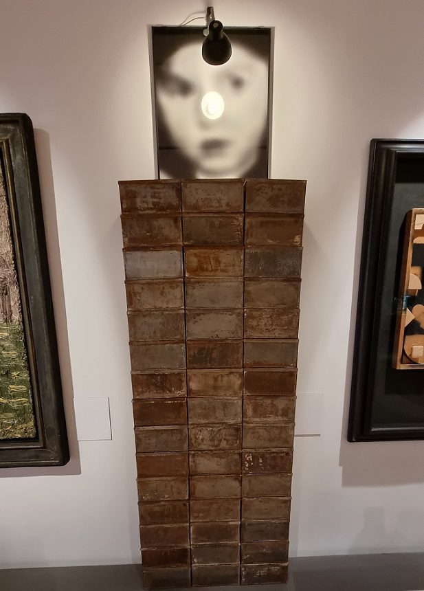 עבודתו של בולטנסקי "מלאי", 54 קופסאות פח, הדפס כסף ג'לטיני ומנורה, 1989 (אוסף נבזלין, אנו - מוזיאון העם היהודי)