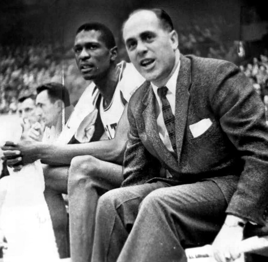 Boston Celtics center Bill Russell sitting on the bench next to head coach Red Auerbach, December 1956 (Jack O'Connell, The Sporting News Archives, Wikipedia)