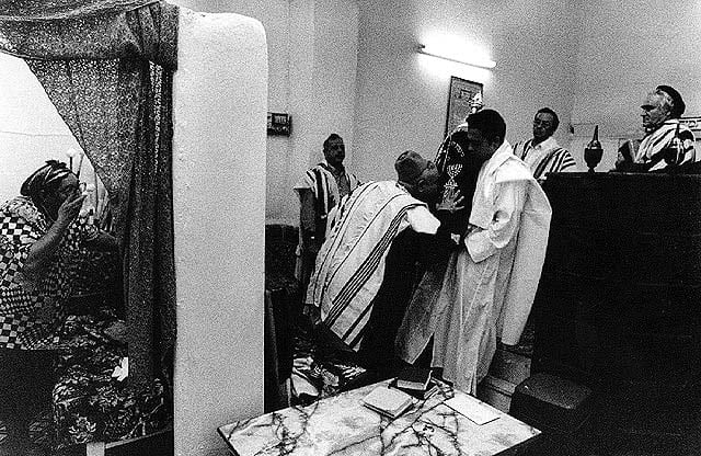 תפילת שחרית בבית הכנסת באינזגאן, מרוקו, 1994. משפחת אסרף היא המשפחה היהודית היחידה שנותרה במקום (צילום: אלכס ליבק. בית התפוצות, המרכז לתיעוד חזותי ע"}ש אוסטר)