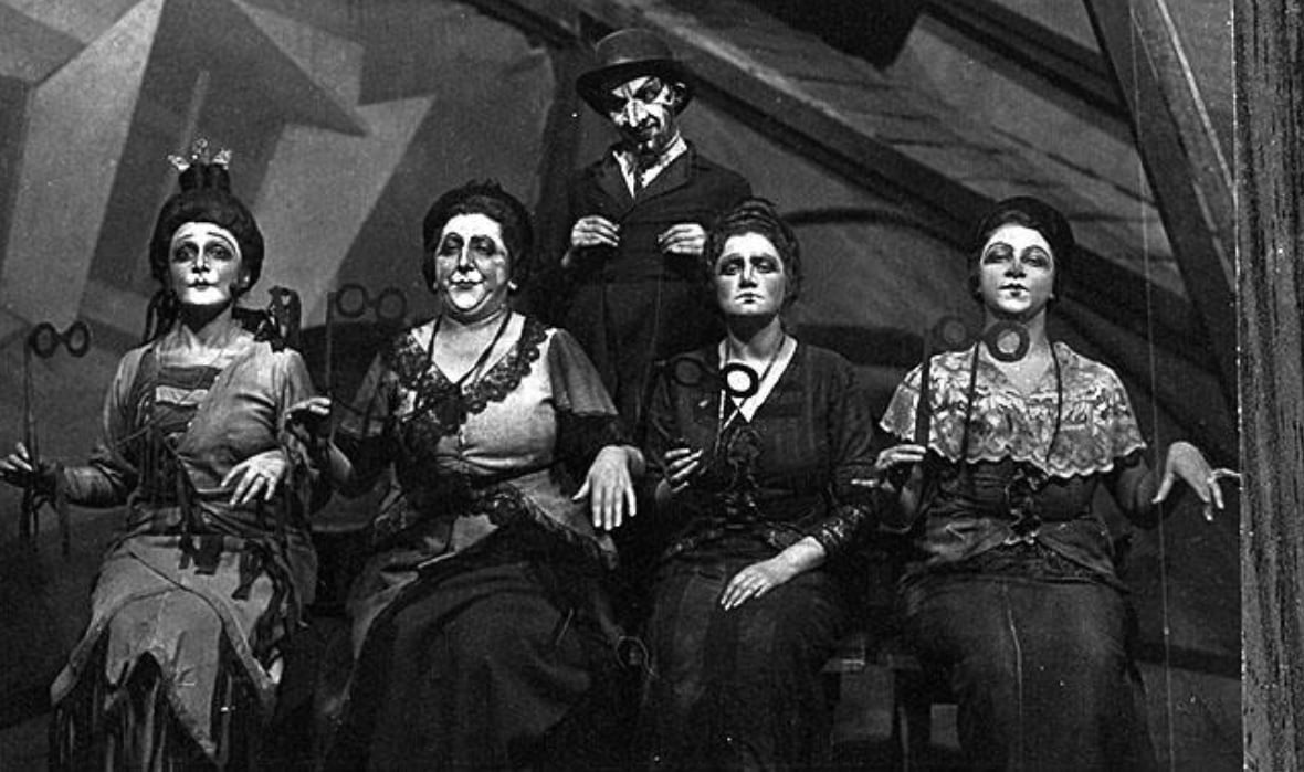 Scene from the play “The Big Win”. Moscow, 1923. Their rigid marionette-like sitting positions represented the way of the wealthy in contrast to the Jewish lower classes. (ANU – Museum of the Jewish People, the Oster Visual Documentation Center, Zuskin collection)